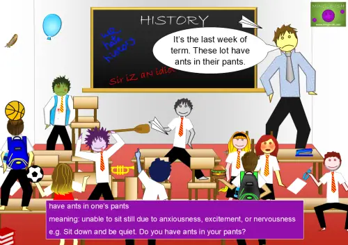 A chaotic classroom scene with children running, jumping, and playing while the teacher looks frustrated. A speech bubble from the teacher says, "It’s the last week of term. These lot have ants in their pants." A definition box at the bottom explains the idiom "have ants in one’s pants," meaning to be unable to sit still due to excitement, anxiety, or nervousness.